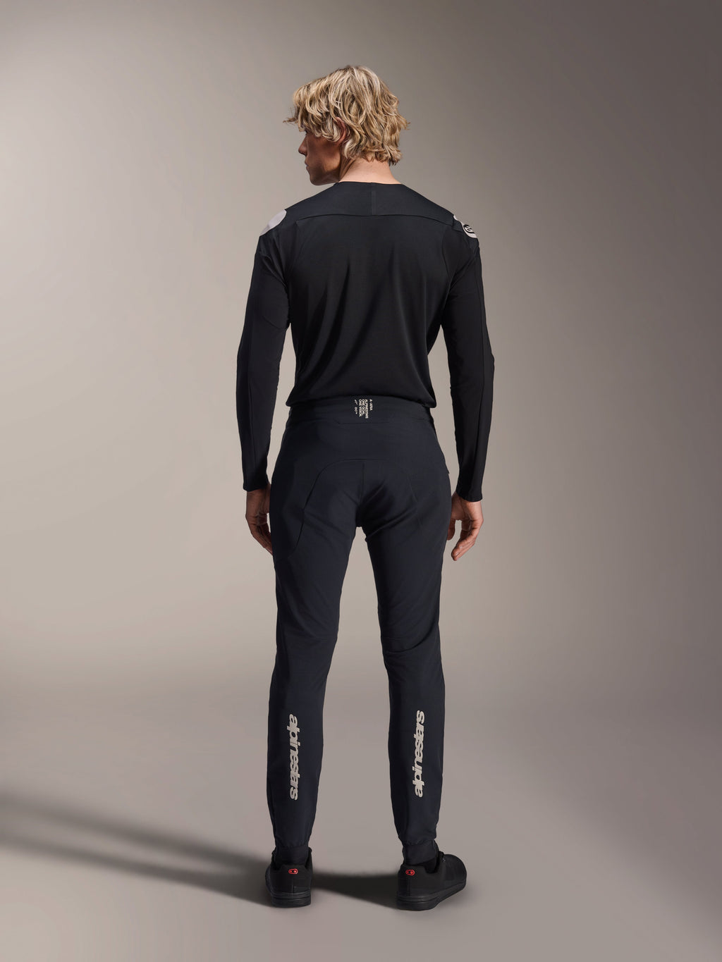 Alpinestars A-Aria Elite Pants, Black Titanium, back view on male model, featuring silver Alpinestars branding on the lower legs, technical MTB pants with a performance fit and moisture-wicking waistband detail.