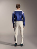 Alpinestars A-Aria Elite Pants in Ecru, shown from the back on a model paired with a blue A-Aria Polartec Maker Elite Long Sleeve Jersey, off-white technical MTB pants featuring black logos on the lower legs, performance cycling gear for mountain biking