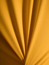 Close-up of orange A-Dura Ride Jersey fabric texture, showing the lightweight jacquard poly/spandex material.