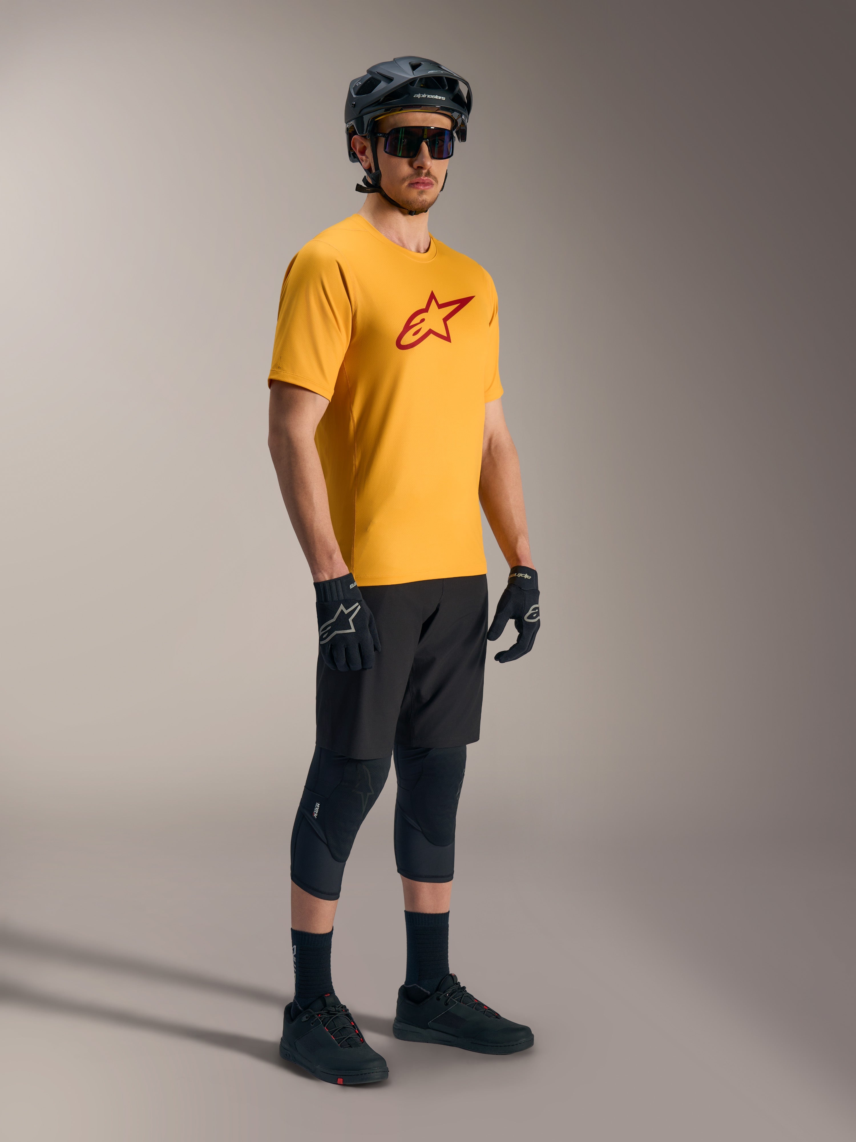Orange A-Dura Ride Short Sleeve Jersey featuring a red Astars logo, paired with black mountain bike gear and helmet.
