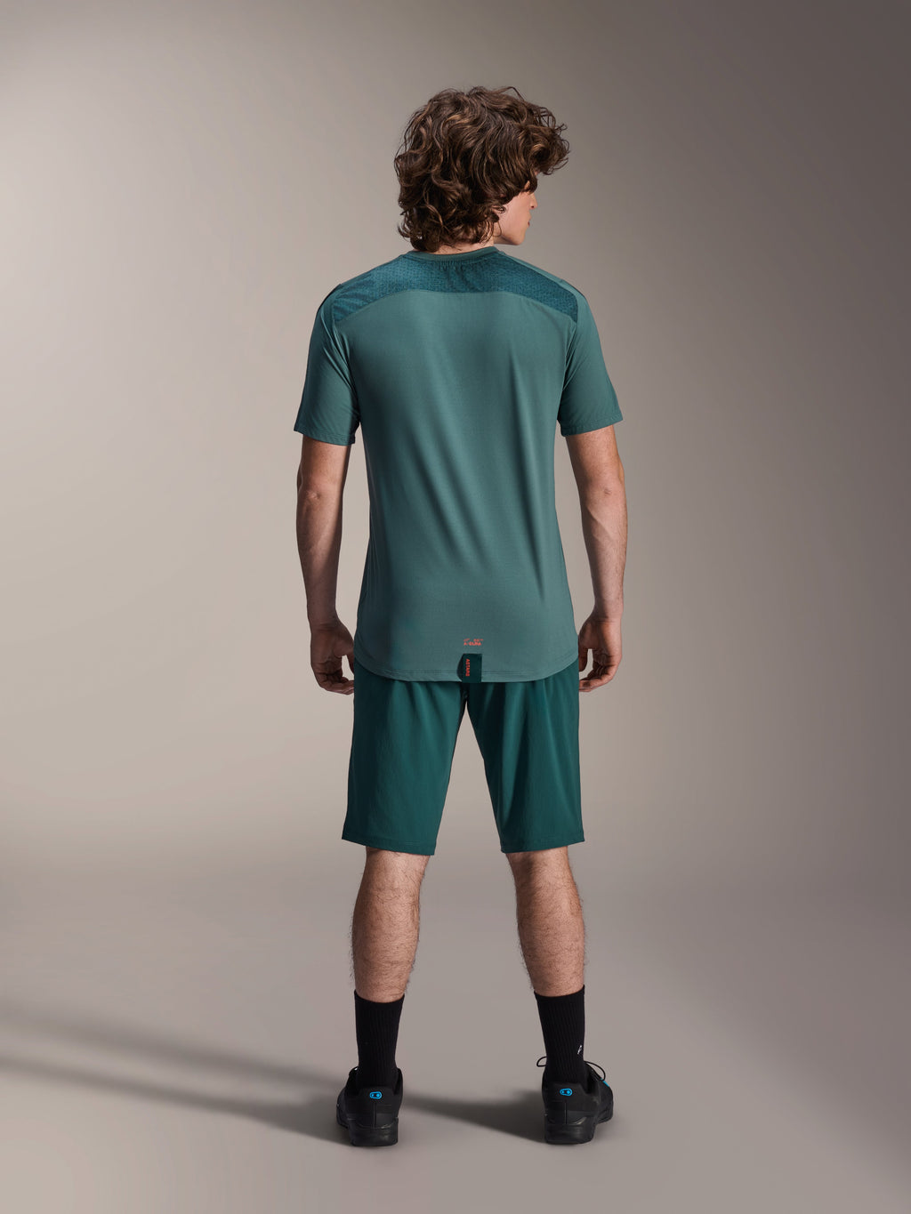 Alpinestars A-Dura Shorts and A-Dura Lipan SS Jersey, Dark Pine green, back view on a model, performance mountain bike apparel featuring short sleeve jersey and matching shorts, off-road cycling outfit