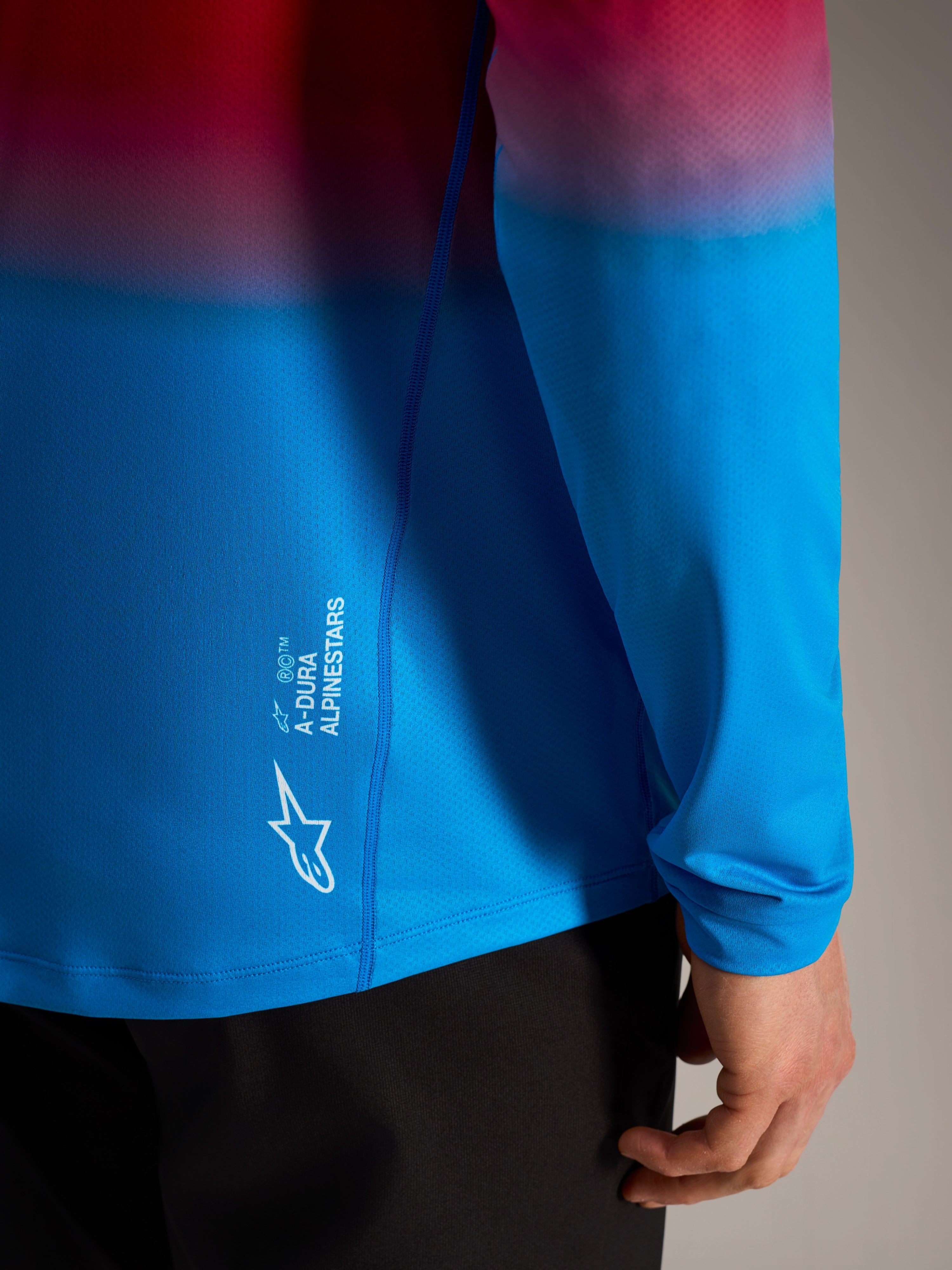 A-Dura ASTARS Long Sleeve Jersey 2.0 in red and blue gradient with white Alpinestars logo branding on the side.
