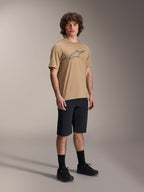 Alpinestars A-Dura Shorts, Black Mountain Bike Shorts, worn by a model with a tan short-sleeve jersey featuring the Alpinestars logo, black socks, and black shoes, durable MTB gear for off-road riding