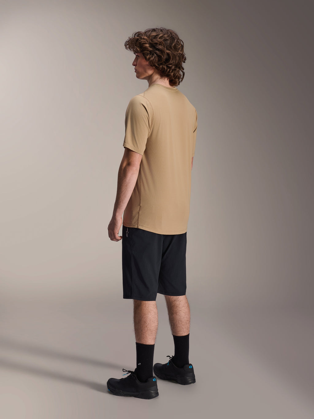 Alpinestars A-Dura Shorts, Mountain Bike Shorts, Black, paired with a tan A-Dura short-sleeve jersey and black riding shoes, featuring a regular fit and durable construction for off-road cycling, rear-side view