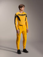 Male model wearing Alpinestars Limited Edition A-Supra Melt Gold Gear-Set, yellow long-sleeve MTB jersey with bold black branding on the chest, matching yellow pants with laser-cut ventilation and black accents, complete mountain bike racing kit.