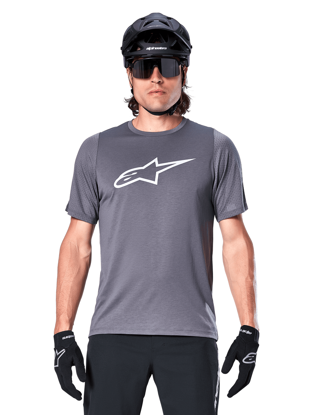 Male mountain biker wearing Alpinestars A-Dura Dri Astar Short Sleeve Jersey, Dark Gray with white Astar logo, paired with a black MTB helmet, sunglasses, and gloves, featuring breathable mesh sleeve panels.