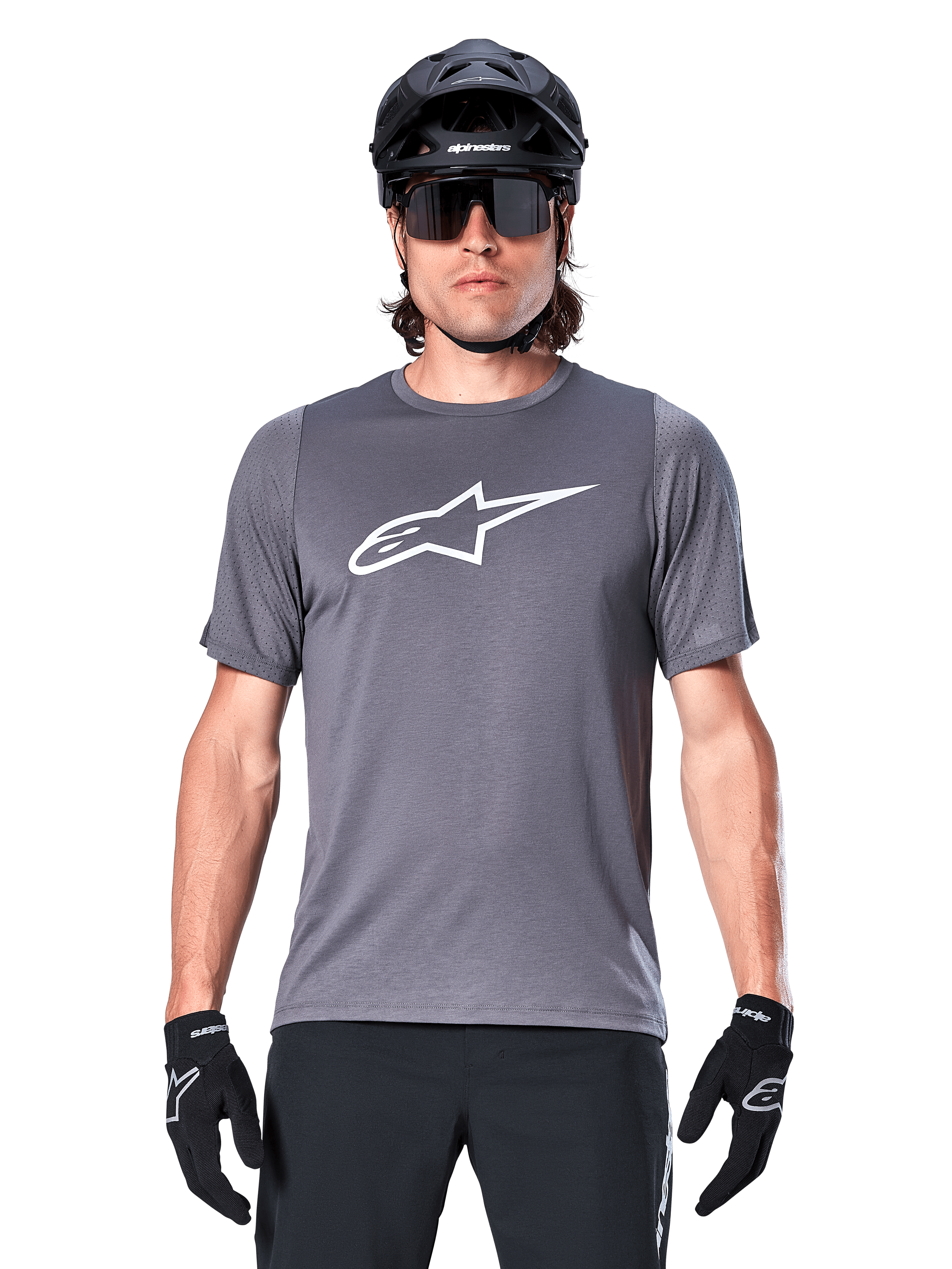 Male mountain biker wearing Alpinestars A-Dura Dri Astar Short Sleeve Jersey, Dark Gray with white Astar logo, paired with a black MTB helmet, sunglasses, and gloves, featuring breathable mesh sleeve panels.