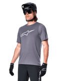 Alpinestars A-Dura Dri Astar Short Sleeve Jersey, Dark Gray, white chest logo and mesh sleeve panels, worn with black MTB helmet, sunglasses, and gloves, performance mountain biking apparel