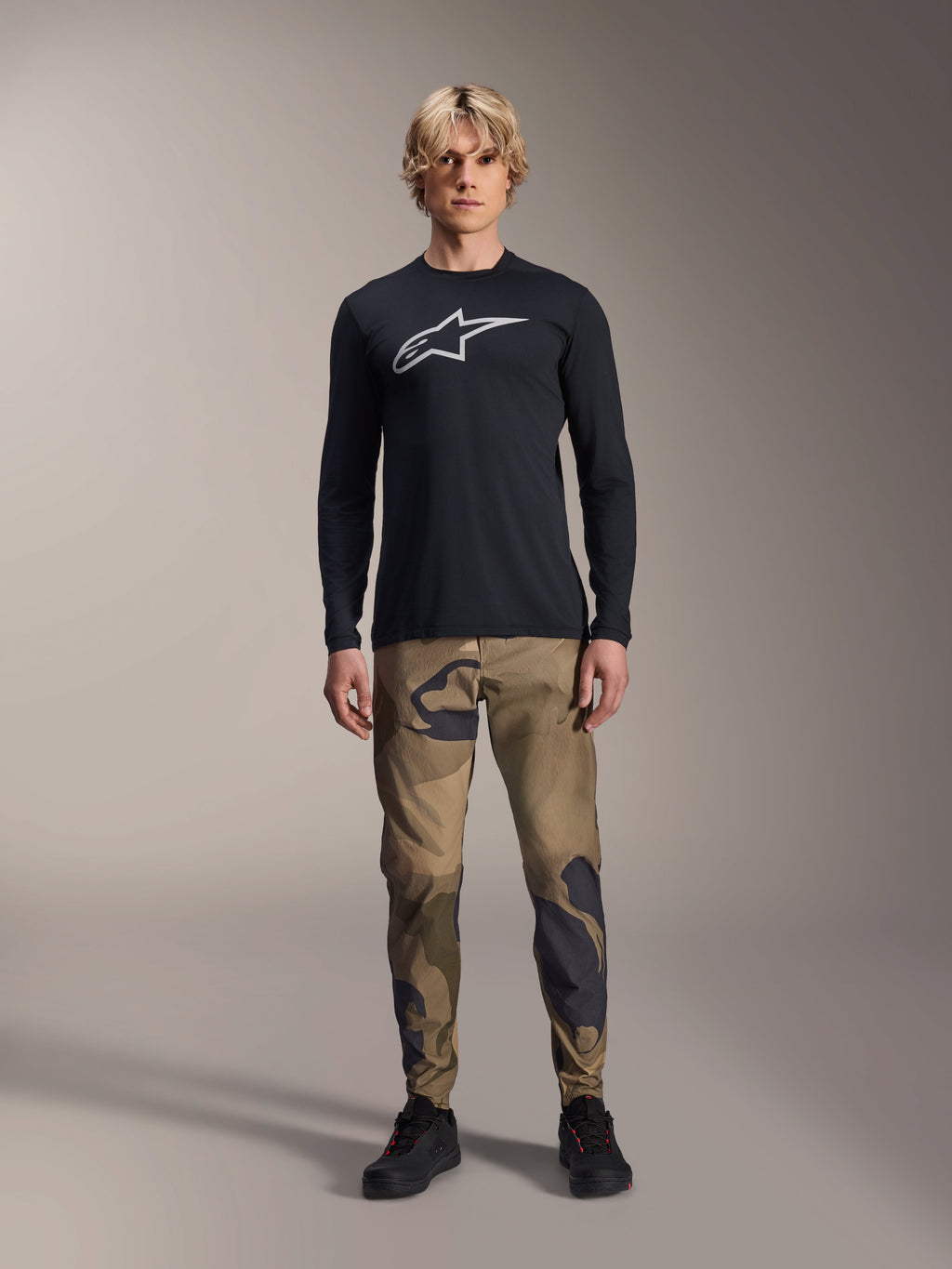 Alpinestars A-Dura Camo Pant, MTB Cycling Pants, Brown and Green Camouflage, worn with a black long-sleeve jersey and black shoes, sporty mountain bike style with durable stretch fabric