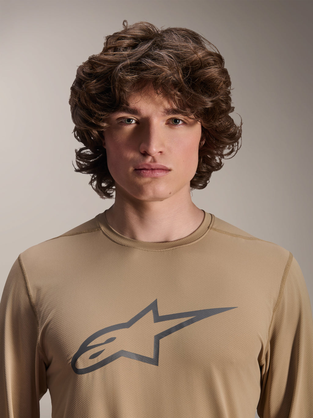Alpinestars A-Dura Astar Long Sleeve Jersey, Light Brown, worn by male model, featuring a large Astars logo on the chest, jacquard fabric texture, casual mountain bike apparel