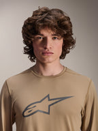 Alpinestars A-Dura Astar Long Sleeve Jersey, Light Brown, worn by male model, featuring a large Astars logo on the chest, jacquard fabric texture, casual mountain bike apparel