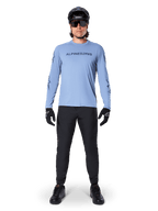 Alpinestars A-Dura Switch Jersey - Long Sleeve, Infinity Blue, worn with black mountain bike pants, black helmet, and sunglasses, featuring a chest wordmark logo graphic, performance cycling apparel for MTB.