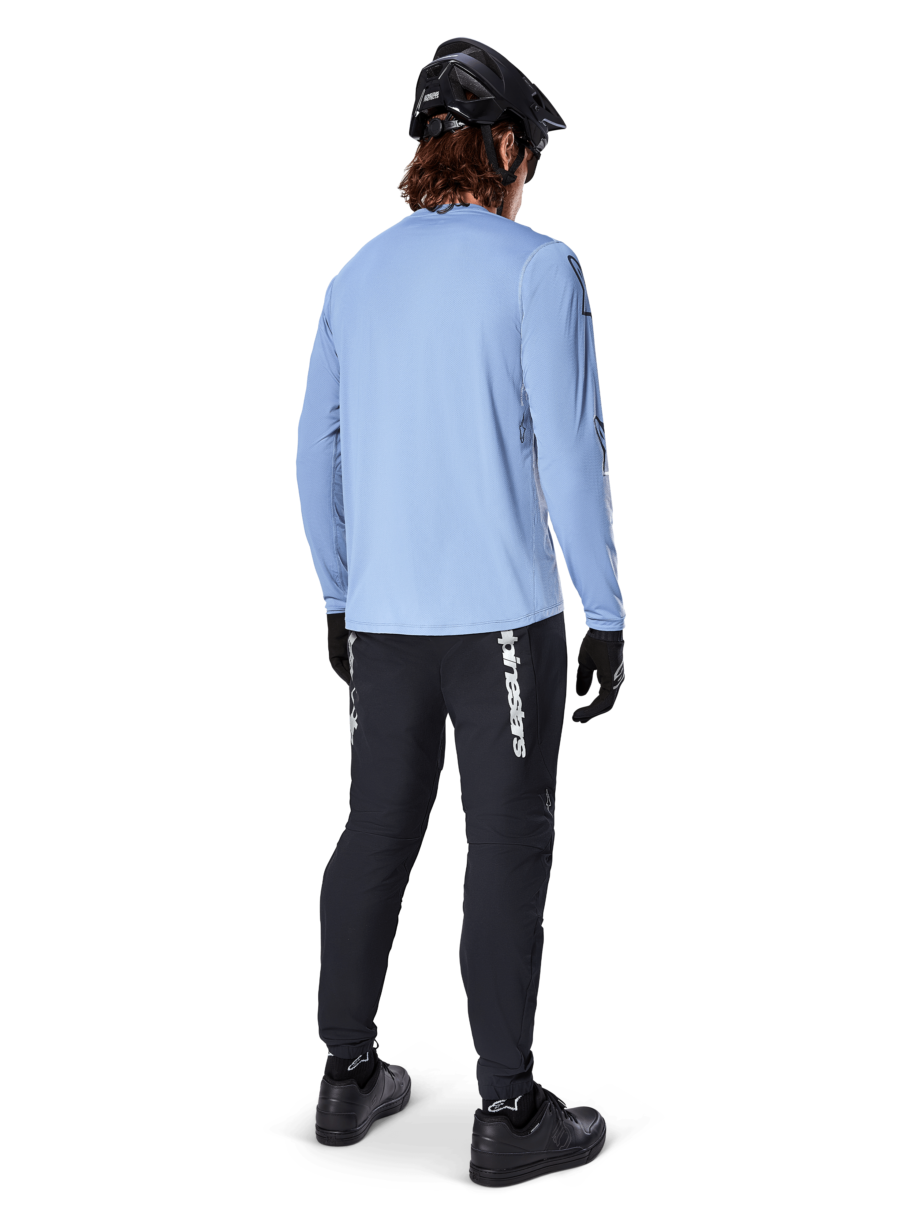 Mountain bike rider from behind wearing Alpinestars A-Dura Switch Long Sleeve Jersey in Infinity Blue, paired with black MTB pants, black helmet, and black shoes, casual trail gear for off-road cycling
