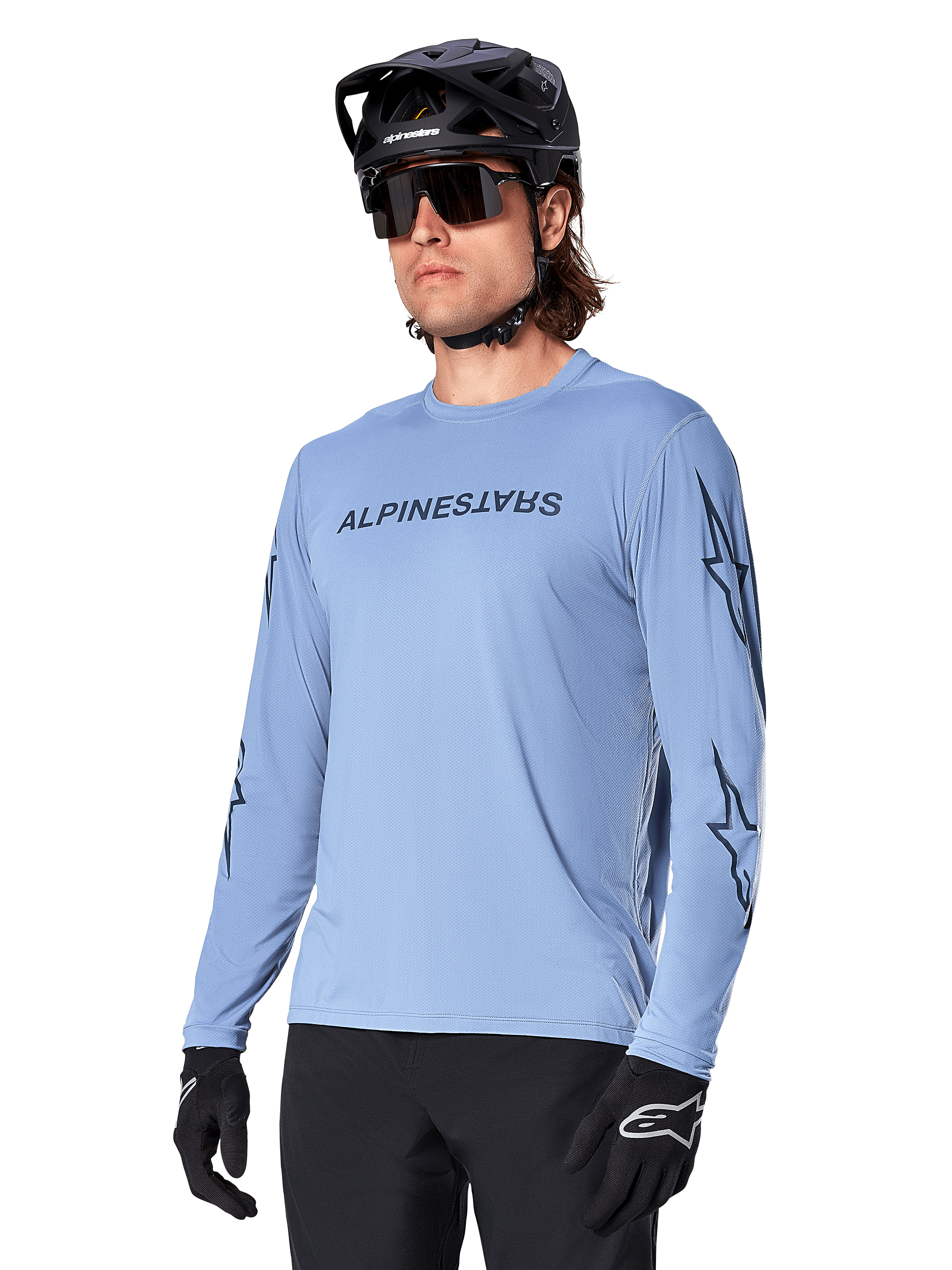 Alpinestars A-Dura Switch Long Sleeve Jersey, Infinity Blue, featuring dark Alpinestars wordmark on the chest and star graphics on the sleeves, worn by a rider with a black mountain bike helmet and sunglasses
