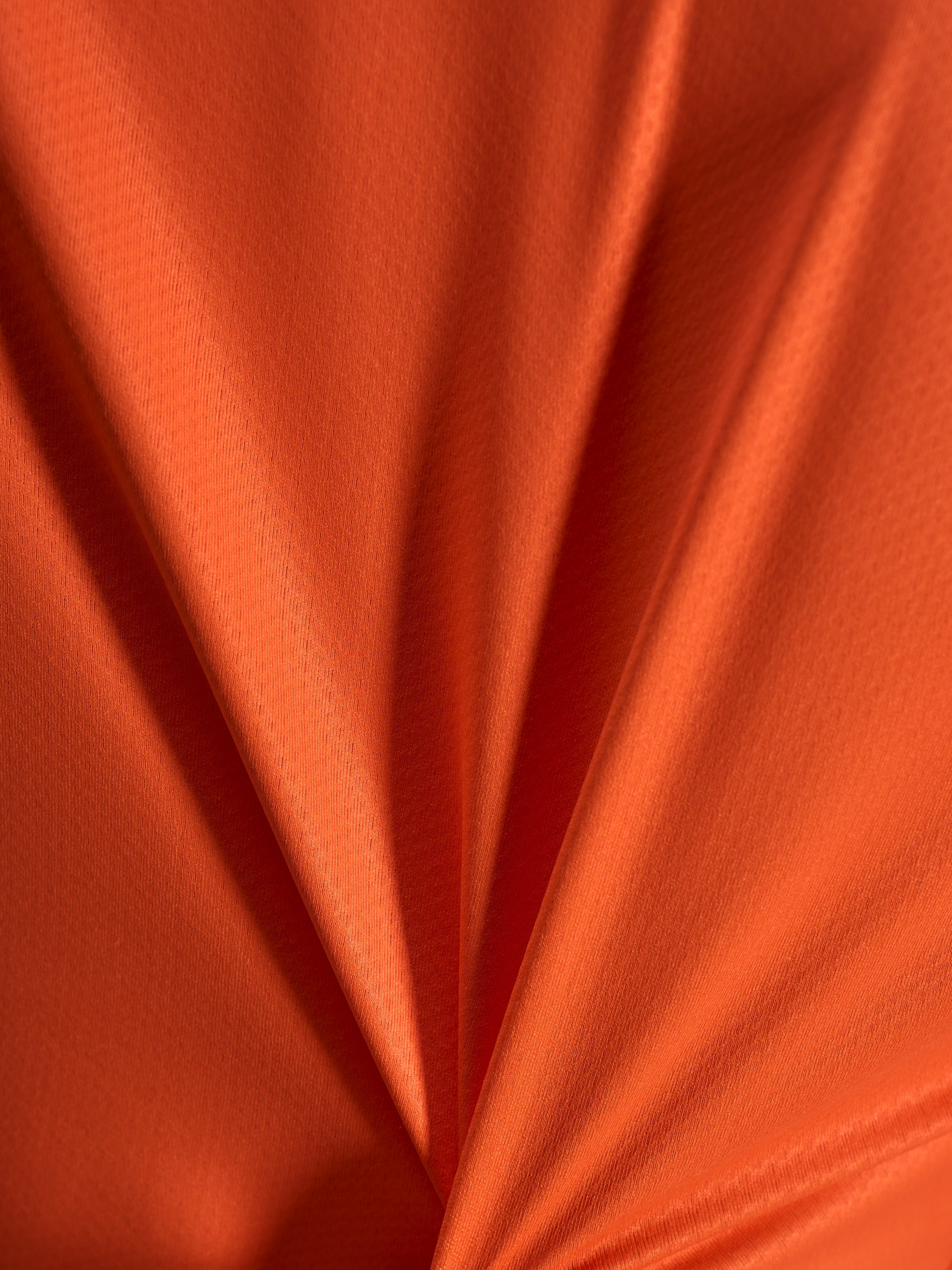 Orange jacquard fabric detail of the Alpinestars Stella A-Dura Ride Jersey, showing its lightweight and stretchy texture.