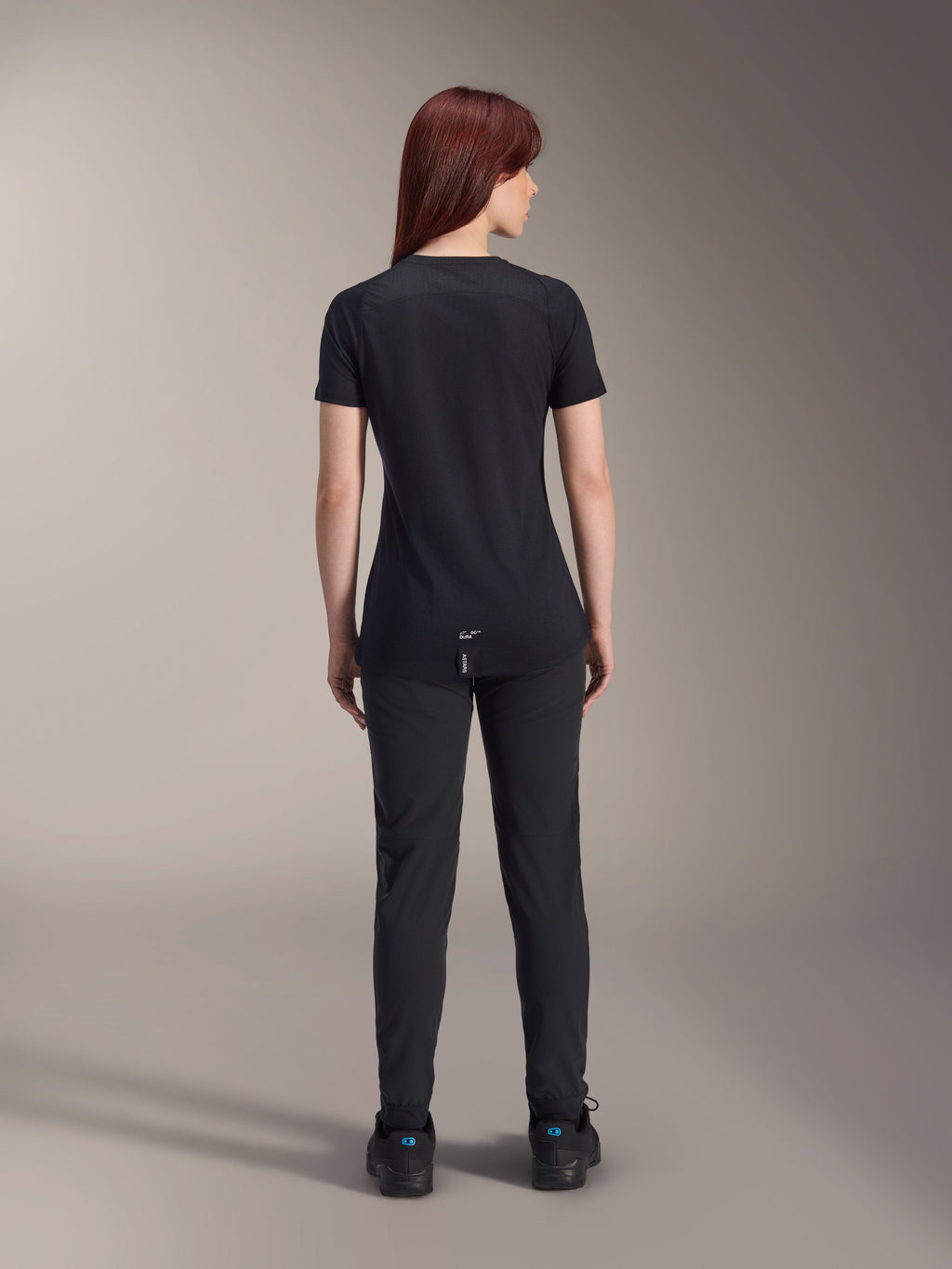 Alpinestars Women Stella A-Dura Dri Switch Short Sleeve Jersey, Black, rear view on a model, featuring a longer drop tail and technical mesh panels, paired with black pants, performance MTB cycling gear