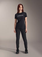 Model wearing Alpinestars Women Stella A-Dura Dri Switch Short Sleeve Jersey in Black, featuring white logo branding on the chest, paired with black technical pants and black athletic shoes, full-body studio shot