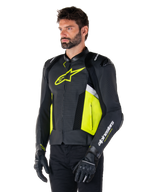 Male model wearing Alpinestars Missile V3 Airflow Leather Jacket, Black with Yellow Fluo and White accents, featuring perforated leather for maximum ventilation, bold yellow logo on the chest, paired with black gloves and pants, sport-style racing motorcycle gear