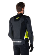 Alpinestars Missile V3 Airflow Leather Jacket, rear view on a male model, black with fluorescent yellow and white accents, featuring extensive perforated leather and mesh panels on the back, branded with a yellow star logo and white 'RACING AHEAD' text, paired with black gloves and pants.