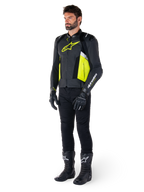Male model wearing the Alpinestars Missile V3 Airflow Leather Jacket in Black, Yellow Fluo, and White, styled with black riding gloves, pants, and boots, showcasing the perforated leather design and racing-inspired aesthetic.