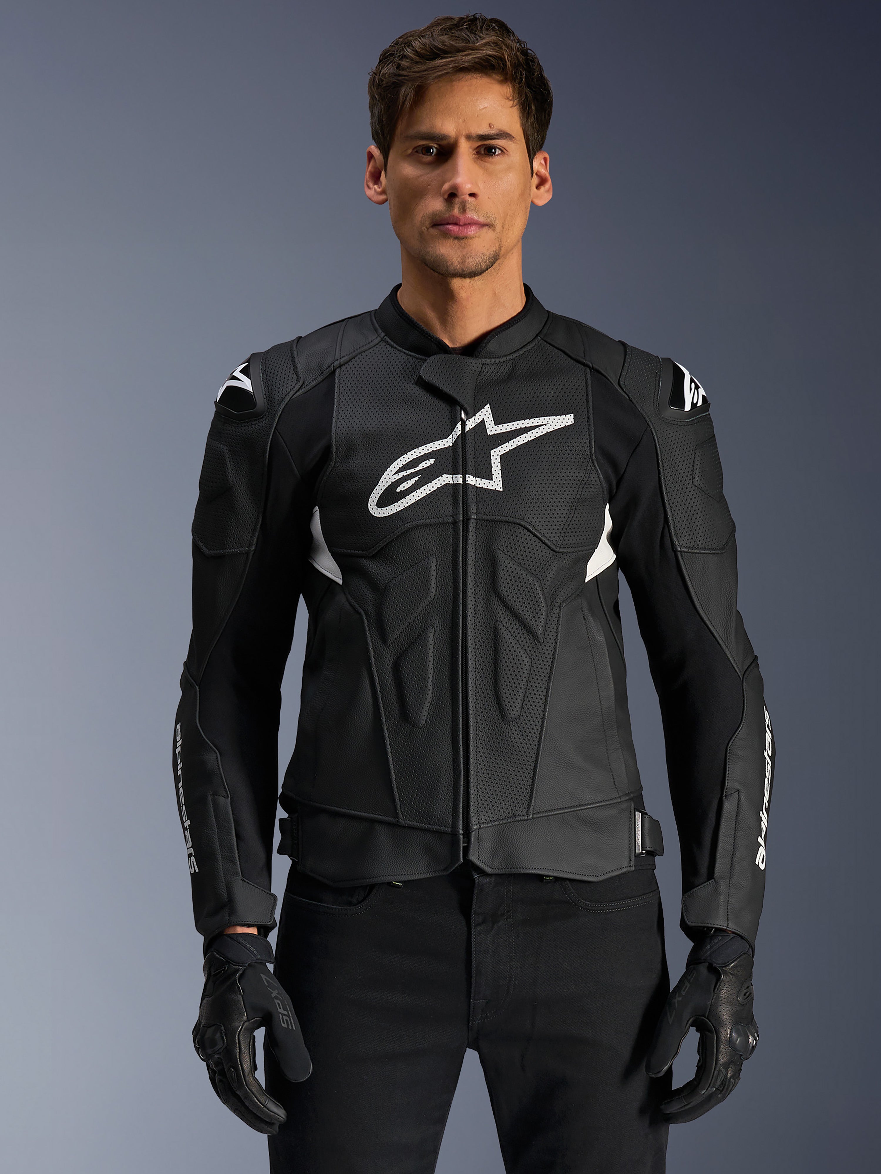 Alpinestars Dusk Airflow Leather Jacket, Black and White, leather motorcycle jacket worn by a model, featuring perforated leather panels for ventilation, a large white chest logo, and external shoulder sliders.