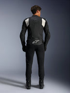 Alpinestars Dusk Airflow Leather Jacket, Black and White, rear view of a rider wearing black pants and boots, featuring perforated leather for ventilation, white accordion stretch panels on the shoulders, and white branding on the lower back