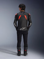 Alpinestars GP Plus R V4 Airflow Leather Jacket, Black Red Fluo and White, rear view on a model, featuring perforated leather panels and bold white branding, styled with black motorcycle pants and boots
