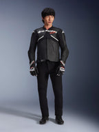 Model wearing the Alpinestars Atem V5 Leather Jacket in Black and White, featuring white Alpinestars branding and a red star logo on the chest, paired with black pants and black and white racing gloves, sleek performance motorcycle gear