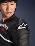 Close-up of the Alpinestars Atem V5 Leather Jacket in Black and White, featuring the DFS RR shoulder protector with white star logo, perforated leather construction, and racing-inspired chest graphics.