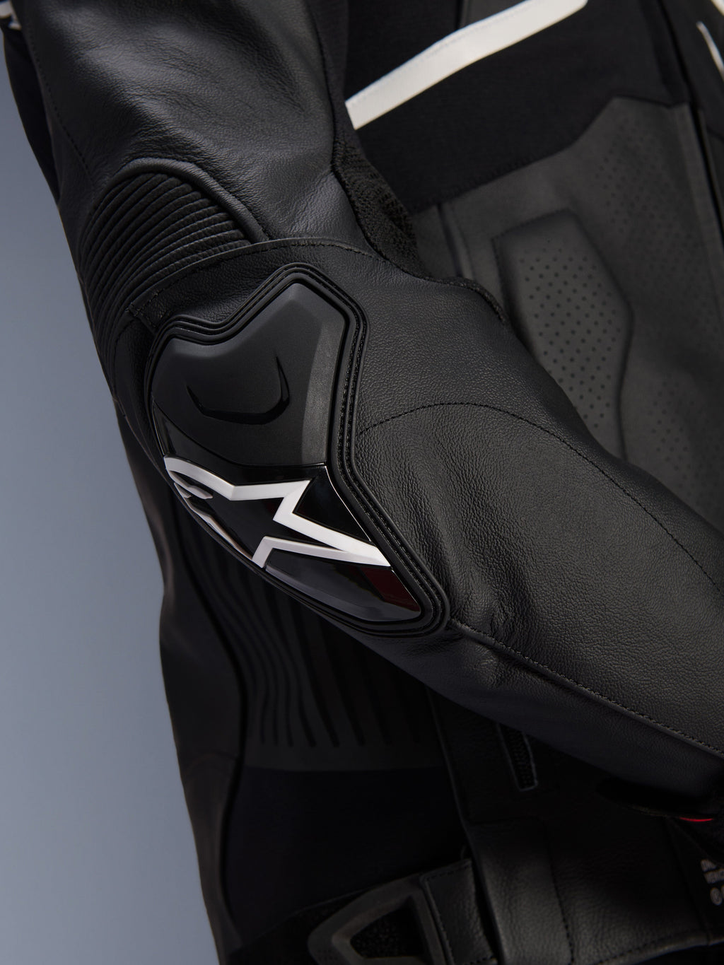 Alpinestars Atem V5 Leather Jacket, Black and White, close-up of the DFS RR elbow protector with white star logo, featuring accordion leather and perforated textures for sport riding