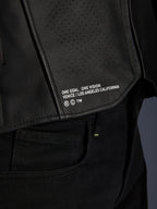 Close-up of the Alpinestars Atem V5 Leather Jacket in Black, featuring the lower back panel with 'ONE GOAL. ONE VISION. VENICE / LOS ANGELES CALIFORNIA' branding and perforated leather texture.