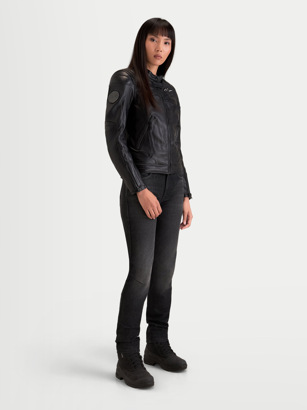 Alpinestars Revea Women Leather Jacket, women's urban contemporary motorcycle jacket in black, three-quarter view on a model wearing dark jeans and riding boots, full-grain bovine leather construction with AA safety rating