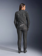 Alpinestars Woman Stella Dusk Leather Jacket, Black, Rear view featuring white Alpinestars logo on the lower back and 'DUSK' branding on the upper back, worn with black riding pants and boots, showcasing the contoured women's fit and protective leather construction.