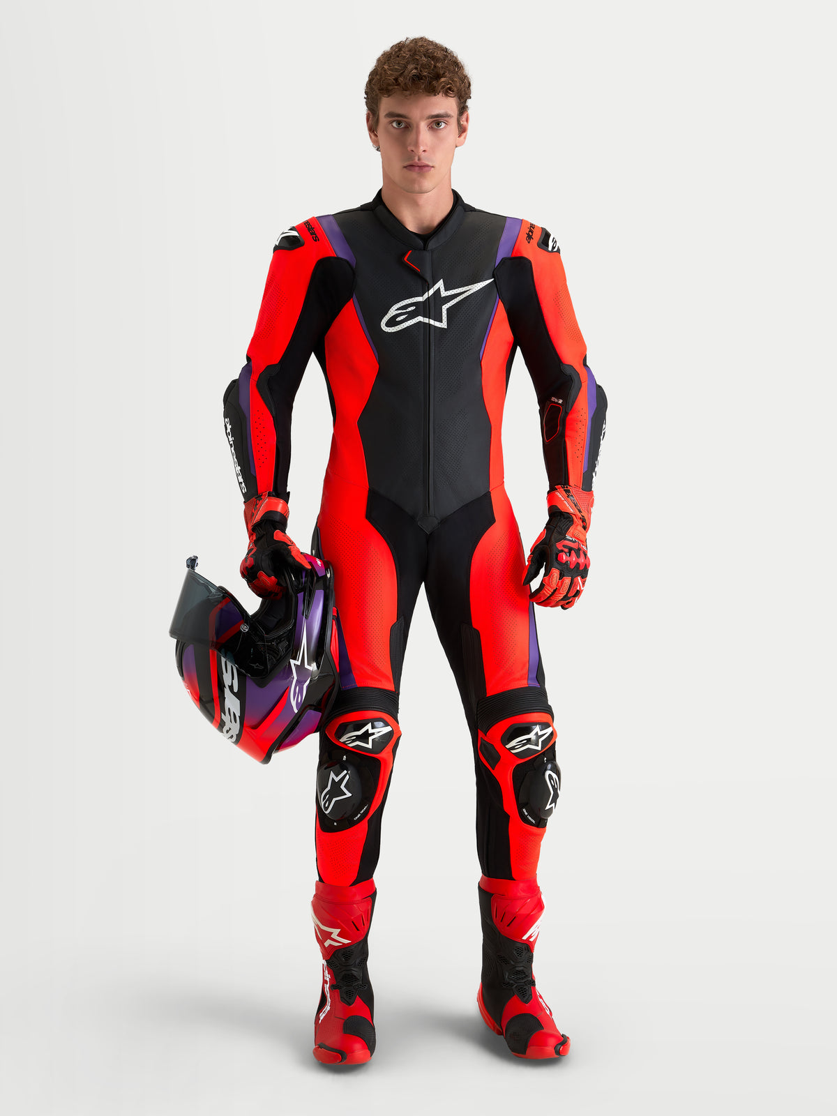 Alpinestars Missile V3 Leather Suit 1 Piece, men's racing leather suit in Black, Red Fluo, and Purple, AAA-rated protection with integrated DFS armor and matching helmet holding context