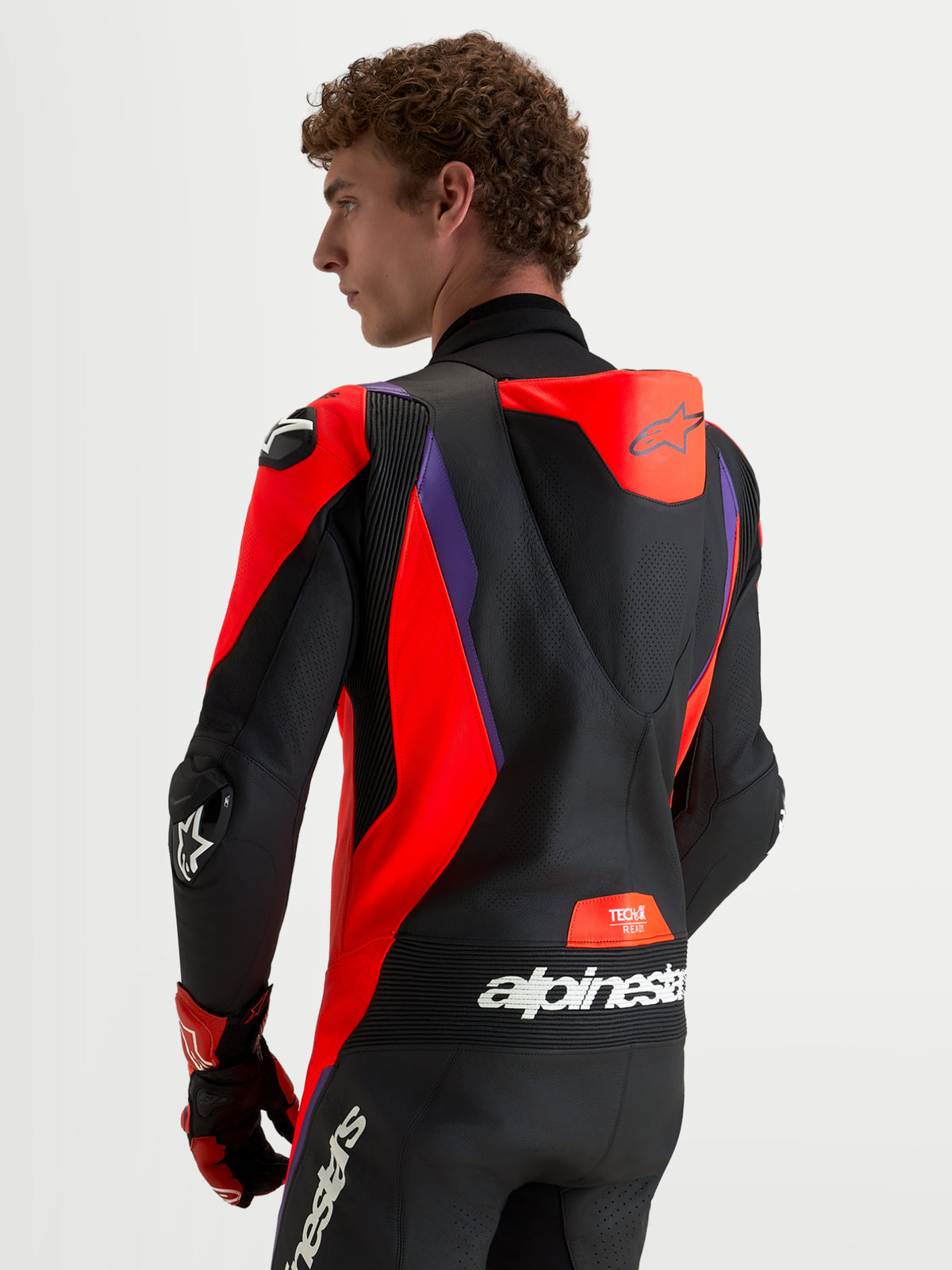 Alpinestars Missile V3 Leather Suit - 1 Piece, men's motorcycle racing suit, Black Red Fluo Purple, featuring a ventilated speed hump, DFS shoulder and elbow armor, and accordion stretch panels, rear view of a model wearing track-ready gear