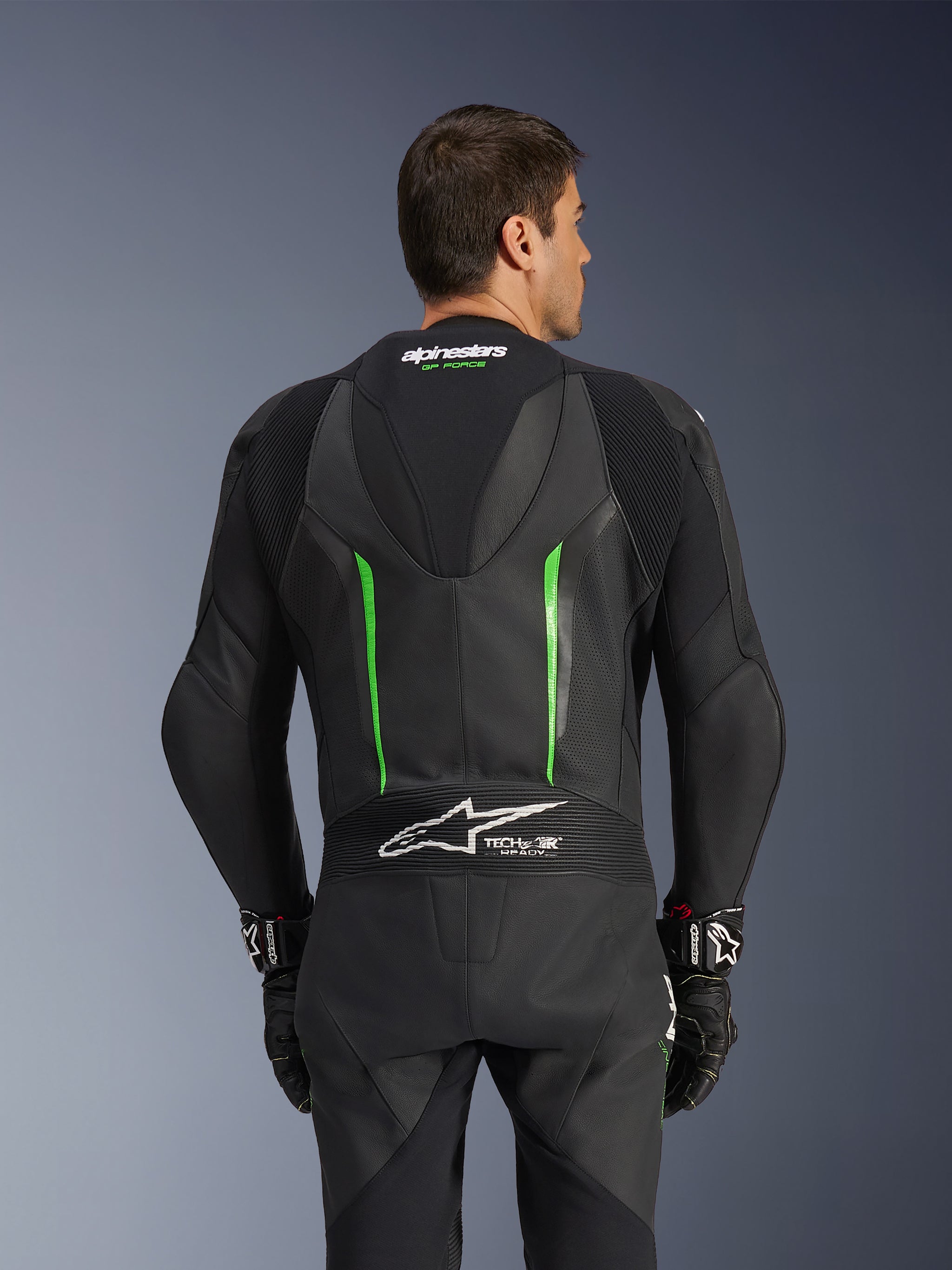 Alpinestars GP Force V2 Leather Suit - 1Piece, Black and Green, back view featuring aerodynamic speed hump, Tech-Air Ready branding, perforated leather zones, and accordion stretch panels for motorcycle racing