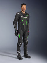 Alpinestars GP Force V2 Leather Suit 1-Piece, Black and Green, full racing gear worn with black gloves and boots, featuring perforated leather panels, white Alpinestars branding, and integrated knee sliders, professional track performance suit