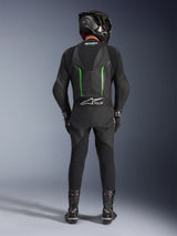 Rider from the back wearing Alpinestars GP Force V2 Leather Suit - 1Piece in Black and Green, paired with a black carbon fiber helmet, black racing gloves, and black boots, featuring an aerodynamic speed hump and Tech-Air Ready branding.