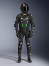 Motorcycle racer wearing Alpinestars GP Force V2 Leather Suit - 1Piece in Black and Green, paired with a carbon fiber helmet and racing gloves, featuring perforated leather panels and white Alpinestars logos, professional track and sport riding gear