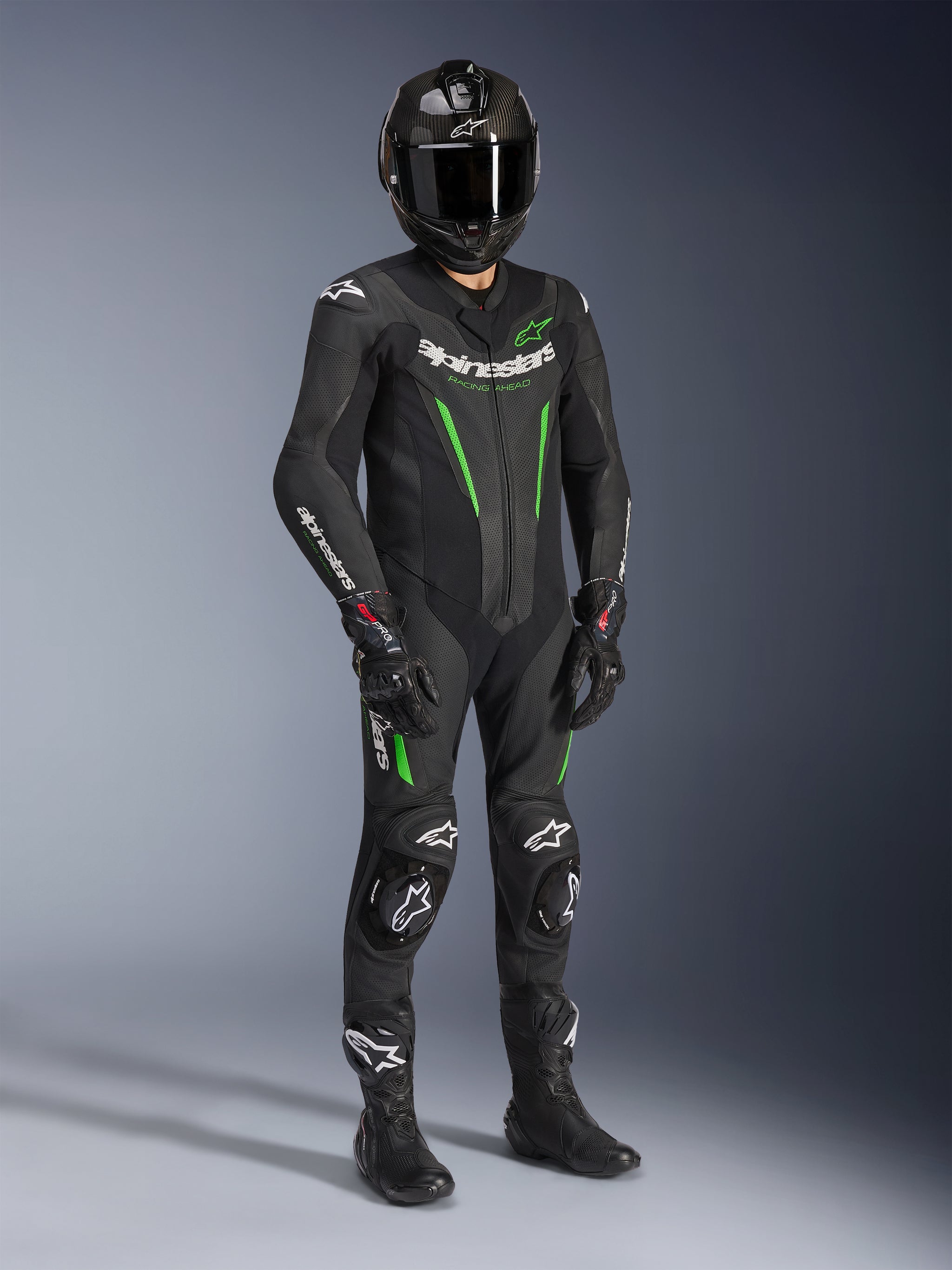 Alpinestars GP Force V2 Leather Suit - 1Piece, Black and Green, worn with matching black helmet, racing gloves, and boots, featuring bright green accents and bold white Alpinestars branding, professional track and sport riding gear