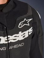 Alpinestars GP Force V2 2-Piece Leather Suit, Racing/Sport Motorcycle Suit, Black, close-up of perforated leather chest with white Alpinestars logo and branding, highlighting ventilation holes and textured construction.