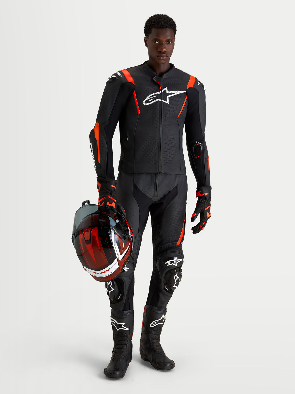 Alpinestars Missile V3 Leather Suit - 2 Piece, Black and Red Fluo men's motorcycle racing suit, featuring AAA-rated leather, aerodynamic race fit, and protective armor while holding a matching helmet