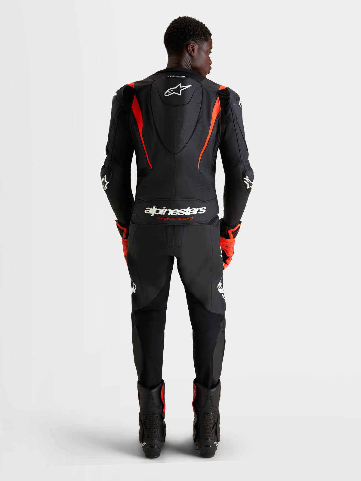 Alpinestars Missile V3 Leather Suit 2 Piece, Men's motorcycle racing leather suit, Black and Red Fluo, featuring aerodynamic speed hump and AAA certified protection, rear view of rider wearing track gear