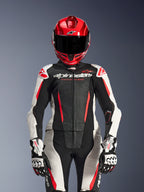 Female rider wearing Alpinestars Stella GP-R7 2-Piece Leather Suit, Black White and Red Fluo colors, featuring perforated panels and 'Racing Ahead' branding, worn with a red helmet and white/black GP Pro gloves, professional racing gear setup