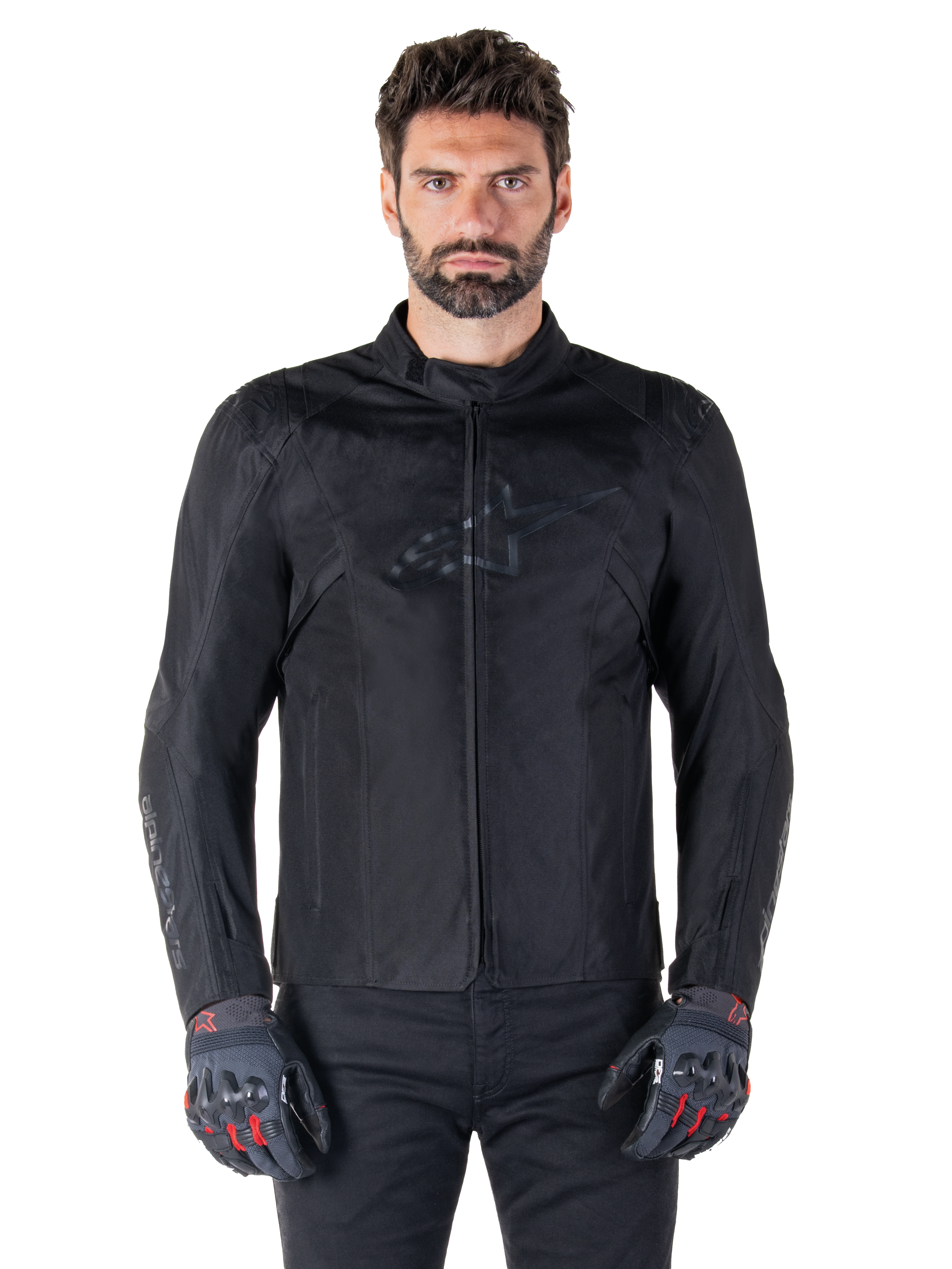 Alpinestars T-SPS V2 Waterproof Jacket, Black motorcycle textile jacket, worn by rider with black and red gloves, featuring a high collar, zippered front, and subtle chest logo, waterproof protection for sport and urban riding