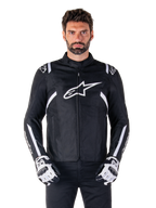 Alpinestars T-SPS V2 Waterproof Jacket in Black and White, front view on model, waterproof textile motorcycle jacket featuring white shoulder and arm stripes, large white Alpinestars logo on chest, worn with protective motorcycle gloves, sleek sport-inspired silhouette
