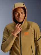 Alpinestars Aeroshell Waterproof Jacket, Dark Khaki Black Orange Fluo, model wearing the jacket with the hood up, featuring vibrant orange fluo trim and an orange ASTARS logo, sleek black accents, modern sport-styled waterproof softshell