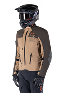 Alpinestars AMT-8 Stretch Drystar® XF Jacket, Adventure Motorcycle Jacket, Dark Brown and Dark Khaki, worn with a black off-road helmet and goggles, featuring Alpinestars Motion Technology branding and zippered ventilation ports.