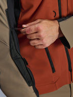 Alpinestars AMT-8 Stretch Drystar® XF Jacket, Walnut Rust Black, close-up of chest ventilation system, hand adjusting a shock cord pull, technical textile with black zippers, detail shot of motorcycle adventure jacket