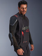 Alpinestars Halo Pro Drystar® XF Laminated Jacket, Black and Dark Shadow, adventure motorcycle jacket worn by model, modular configuration featuring mesh sleeves with integrated shoulder and elbow armor, red logo accents and technical waterproof zippers.